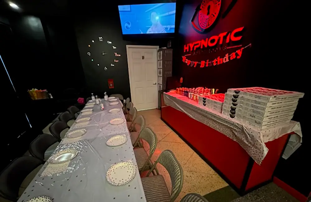 The lobby table set with plates and glasses under the wall-mounted screen