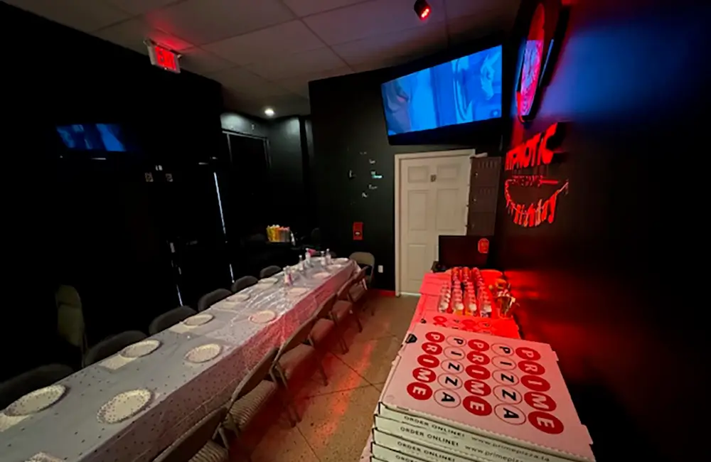 Pizza boxes and place settings down the length of the lobby table, screens overhead