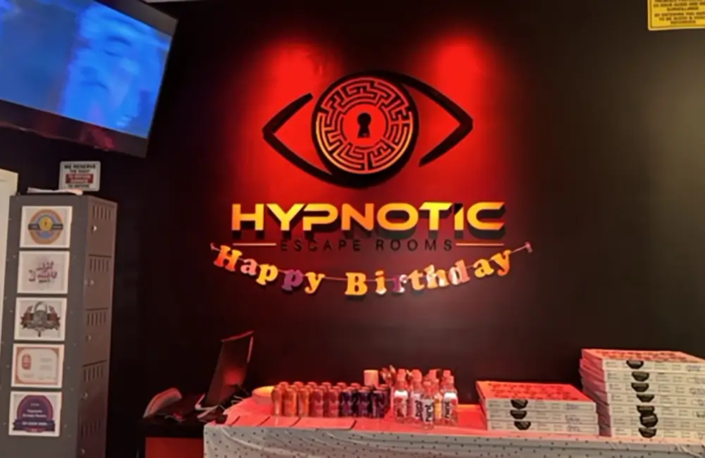 A catering spread laid out along the counter beneath the red 'Hypnotic — Happy Birthday' logo wall