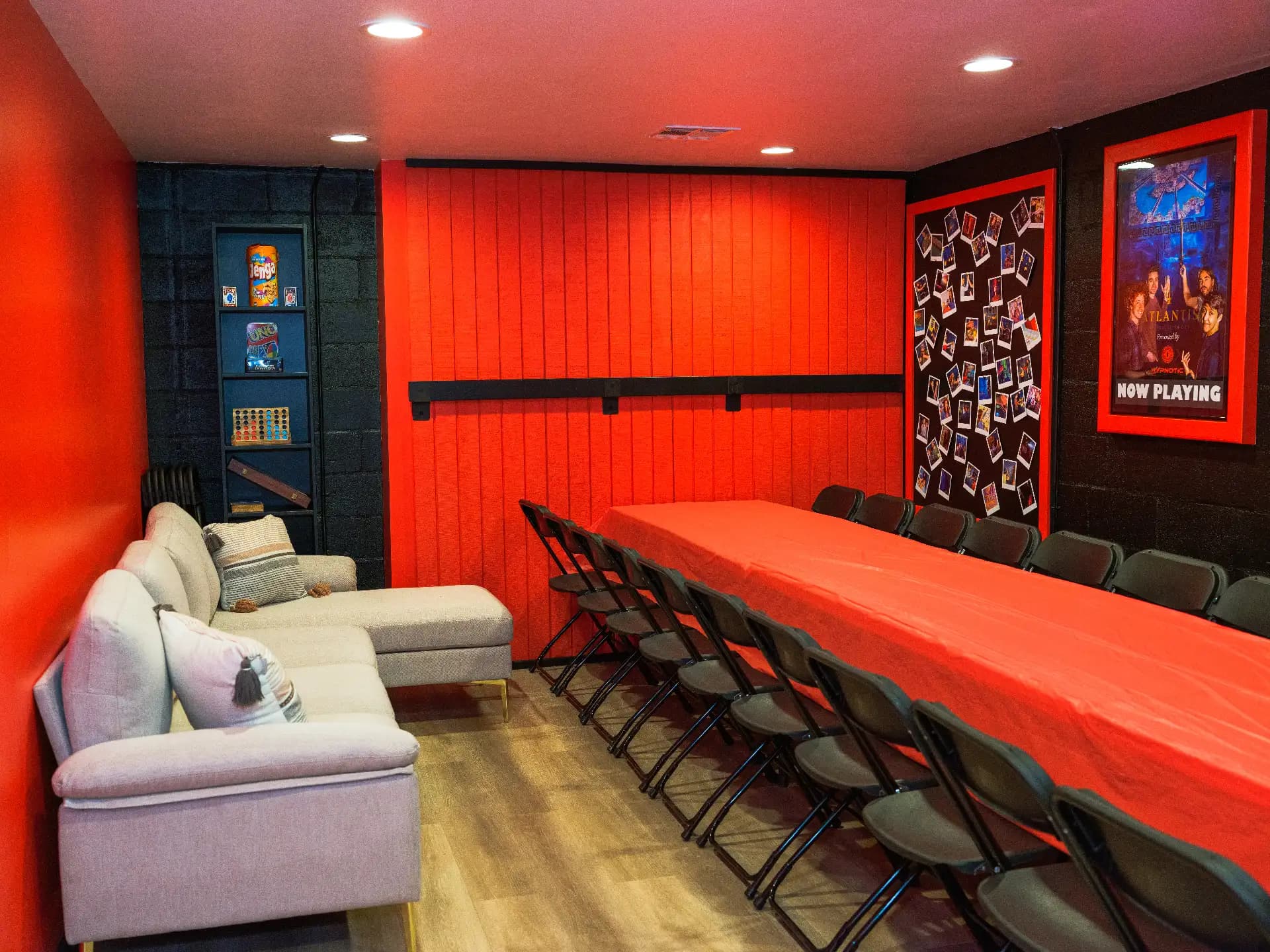 Lounge seating and the banquet table running the length of the private party room under warm red lighting